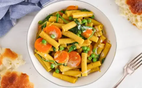 Makaron z mlekiem kokosowym i curry, z marchewką i groszkiem. Kremowy sos otula złociste rurki, tworząc aromatyczne danie.