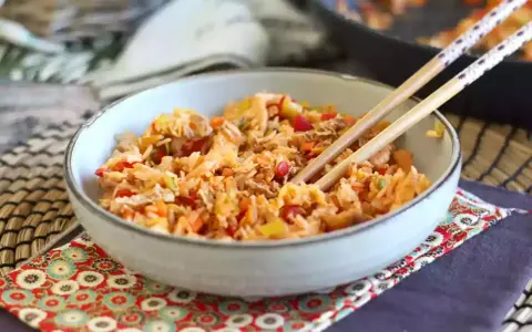 Miseczka pełna aromatycznego nasi goreng z warzywami i kawałkami mięsa, gotowa do jedzenia pałeczkami.