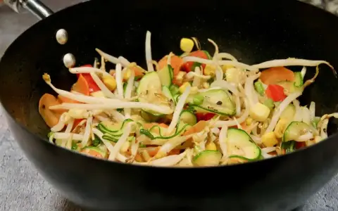Kolorowe warzywa teriyaki w woku: kiełki fasoli mung, cukinia, marchewka, papryka i kukurydza.