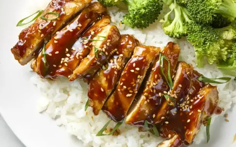 Pyszny kurczak w marynacie teriyaki, podany z ryżem i brokułami. Posypany sezamem i szczypiorkiem.
