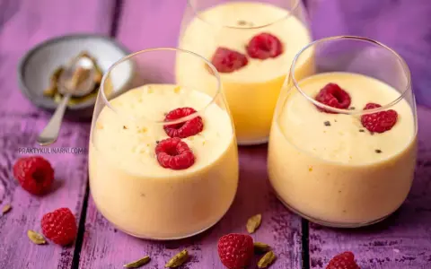 Pyszny jogurt z mango, udekorowany malinami i kardamonem, kusi swoim tropikalnym smakiem.