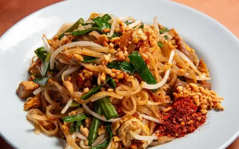 Pyszny pad thai z ryżowym makaronem, kiełkami, orzeszkami i chili. Idealny makaron do pad thai to cienki, płaski ryżowy.