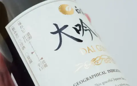 Butelka sake z napisem "DAI GIN". Na etykiecie widać skalę smaku i temperatury podania.