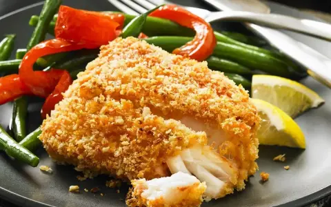 Chrupiący filet rybny w japońskiej panierce, podany z fasolką szparagową, papryką i cytryną.