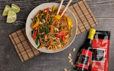 Kolorowy makaron wok z warzywami i orzeszkami ziemnymi, podany z sosami House of Asia.