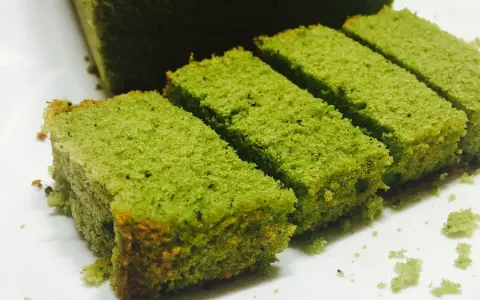Puszyste ciasto matcha pokrojone w prostokątne kawałki, ułożone na białym talerzu.