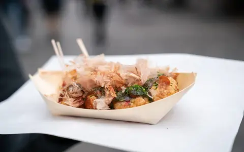 Pyszne takoyaki, czyli japońskie kulki z ośmiornicą, posypane płatkami bonito i zieloną posypką. Idealny japoński street food na wynos.