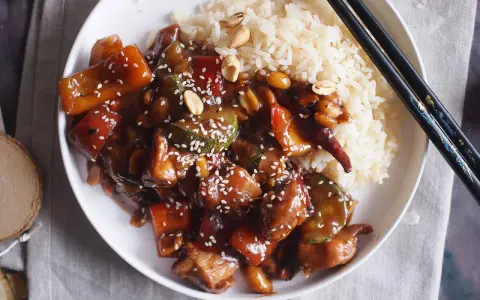 Pyszne danie kung pao z kurczakiem, warzywami i orzeszkami ziemnymi, podane z ryżem.