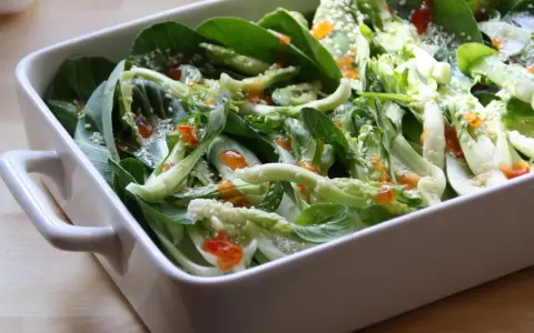Pyszna kapusta pak choi po tajsku, polana sosem i posypana sezamem, w białej ceramicznej misie.
