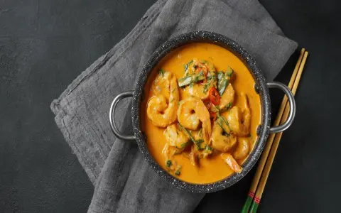 Aksamitne tajskie curry z krewetkami, podane w garnuszku z pałeczkami.