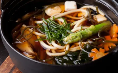 Aksamitny bulion dashi, w którym pływają grube kluski udon, tofu, marchewki w kształcie kwiatków, zielone warzywa i wodorosty. Pyszne i zdrowe danie.