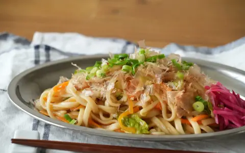 Udon z warzywami i szczypiorkiem, posypany płatkami katsuobushi. To właśnie katsuobushi co to jest, suszone płatki bonito, dodają daniu głębi smaku.