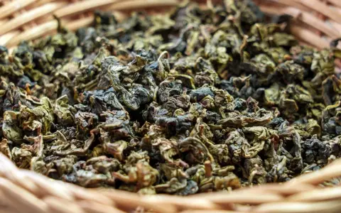 Suszone liście herbaty gunpowder w wiklinowym koszyku. Odkryj jej niezwykłe właściwości!