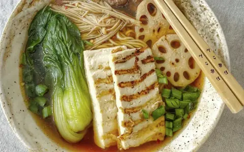 Aksamitny vege ramen z grillowanym tofu, pak choi, grzybami enoki i plasterkami lotosu. Idealny na chłodny wieczór.