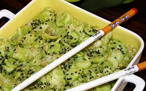 Pyszne ogórki po japońsku, posypane czarnym i białym sezamem, gotowe do jedzenia pałeczkami z motywem sushi.