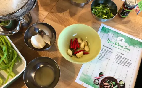 Składniki do zupy **sos tom yum**: czosnek, chili, zielona cebulka, makaron i pasta **sos tom yum** w słoiczku.