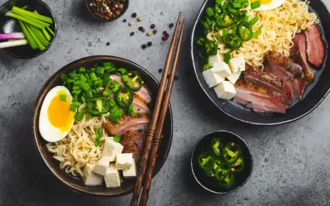Pyszny ramen wołowy przepis: makaron, plastry mięsa, jajko, tofu, szczypiorek i papryczki jalapeño.