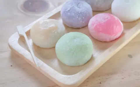 Kolorowe mochi, czyli japońskie ciastka ryżowe, na drewnianej tacy. Zastanawiasz się mochi co to? To pyszna, miękka przekąska!