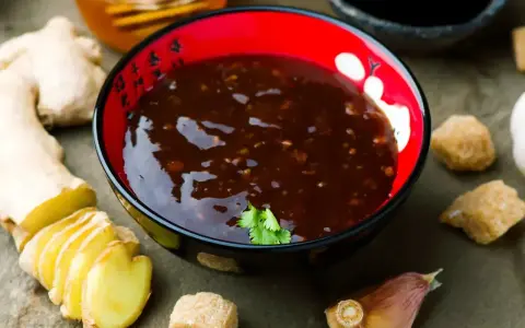 Aksamitny sos teriyaki w misce, obok świeży imbir, czosnek i brązowy cukier. Idealny do wieprzowiny.