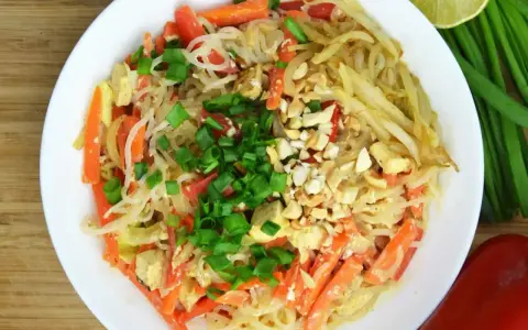 Talerz pełen pad thai z marchewką, tofu i orzeszkami ziemnymi. Zastanawiasz się nad pad thai kcal?
