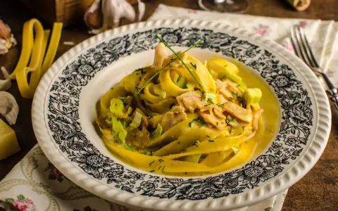 Pyszny makaron curry z kurczakiem i porem w kremowym sosie, ozdobiony szczypiorkiem.