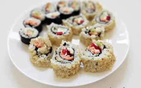 Talerz pełen sushi uramaki z łososiem, awokado i papryką, posypane sezamem. Pyszne i kolorowe rolki.