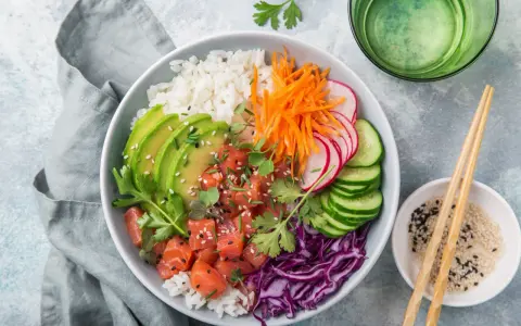 Kolorowy poke bowl: ryż, łosoś, awokado, marchewka, rzodkiewka, ogórek i czerwona kapusta. Idealny posiłek, który zaspokoi głód.