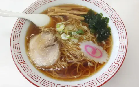 Miseczka aromatycznego ramenu, dania, którego **ramen skąd pochodzi** jest z Japonii. Widać makaron, plastry mięsa, nori, bambus i narutomaki.