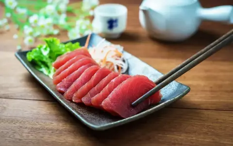 Pyszne japońskie ryby, świeże sashimi z tuńczyka, podane z sałatką i sosami. Pałeczki gotowe do degustacji.