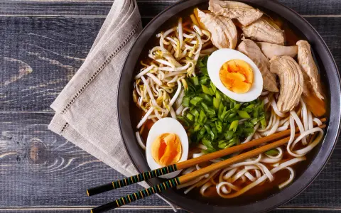 Pyszny shoyu ramen z kurczakiem, jajkiem na twardo, kiełkami fasoli mung i szczypiorkiem.