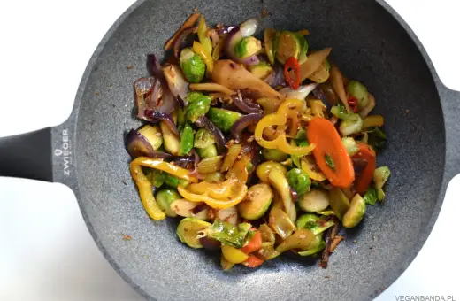Kolorowe warzywa stir fry z brukselką, papryką i marchewką na patelni.