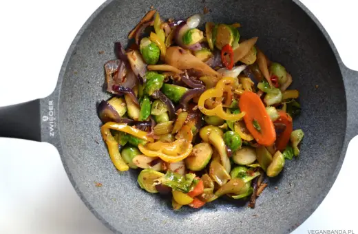 Kolorowe warzywa stir fry z brukselką, papryką i marchewką na patelni.