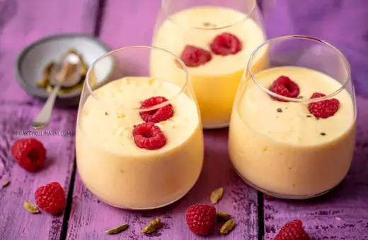 Pyszny jogurt z mango, udekorowany malinami i kardamonem, kusi swoim tropikalnym smakiem.