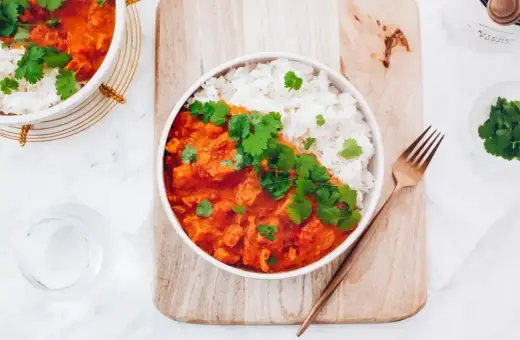 Pyszny red curry przepis z kurczakiem i ryżem, udekorowany świeżą kolendrą. Idealny na obiad.