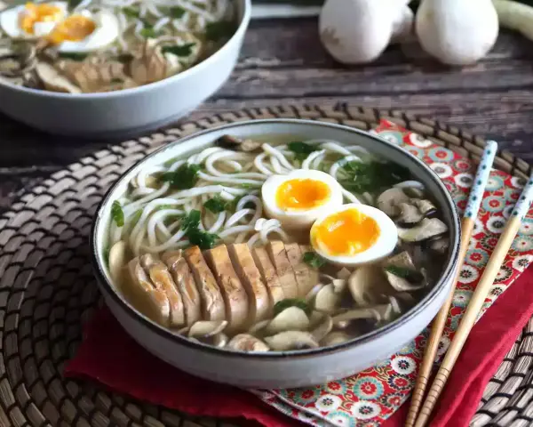 Pyszne ramen z kurczakiem, jajkiem na pół i grzybami. Aromatyczny bulion i delikatny kurczak tworzą idealne danie.