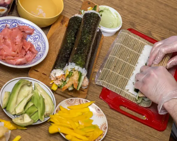 Przygotowanie sushi: ryż, awokado, mango, krewetki i marynowany imbir czekają na rolki. Zobacz nasz sushi przepis!