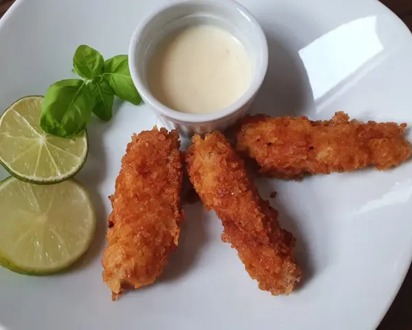 Chrupiąca ryba w panko, podana z sosem i limonką, wygląda apetycznie.