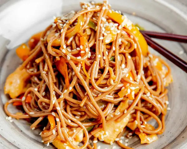 Soba z kurczakiem i warzywami, posypana sezamem. Pyszny przepis na soba, idealny na szybki obiad.