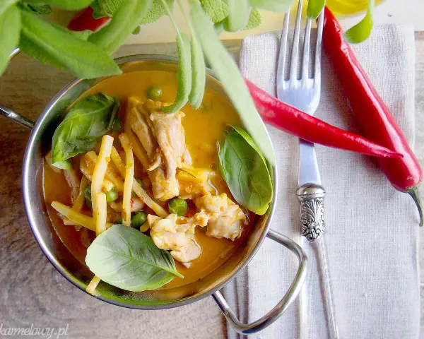 Aromatyczne czerwone curry z kurczakiem, bambusem i groszkiem, ozdobione świeżą bazylią i papryczkami chili.