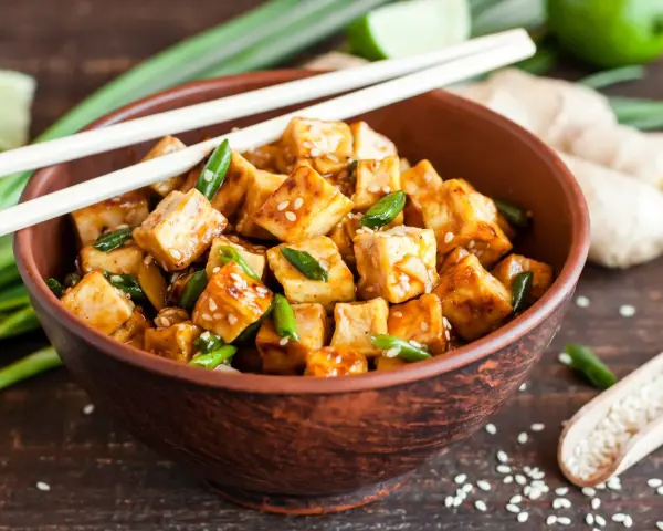 Miseczka pysznego, glazurowanego tofu z sezamem i szczypiorkiem. Zastanawiasz się, ile kcal ma tofu? To zdrowe i sycące danie!
