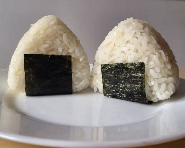 Dwa ryżowe onigiri z nori, gotowe do spożycia. Idealne nadzienie do onigiri sprawia, że są pyszne.