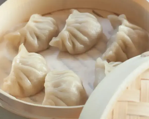 Aksamitne pierożki na parze w bambusowym koszyku, parujące i gotowe do jedzenia.