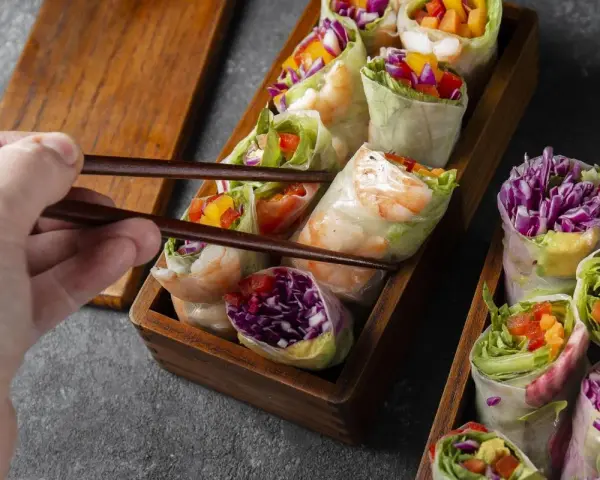 Chwytam pałeczkami świeże sajgonki z krewetkami, czerwoną kapustą i warzywami. Idealne co do sushi!