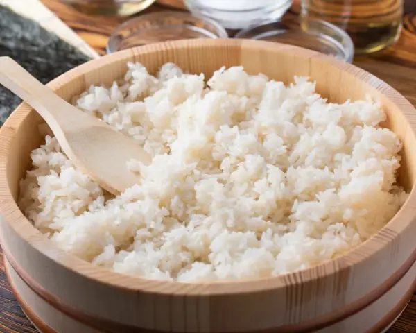 Gotowy do sushi ryż w drewnianym naczyniu, obok nori i składników. Różne rodzaje ryżu do sushi są kluczowe.