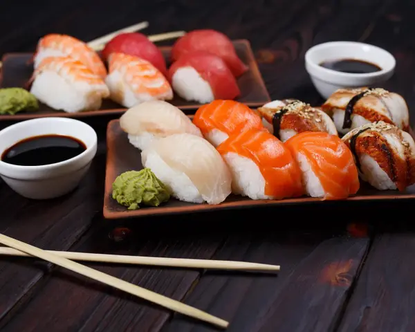 Wyśmienite japońskie sushi: nigiri z łososiem, rybą maślaną i krewetką, podane z wasabi i sosem sojowym.