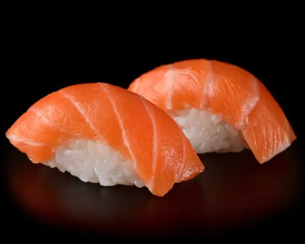 Dwa kawałki sushi z łososiem, idealna ryba do sushi, na czarnym tle.