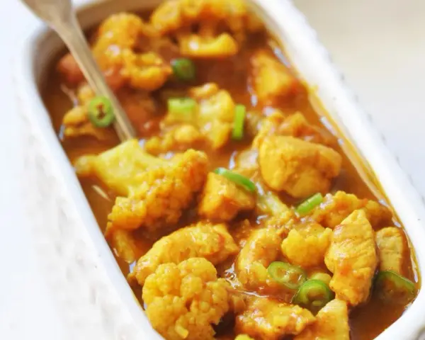 Aromatyczne curry z kurczakiem i kalafiorem w kremowym sosie, posypane zieloną papryczką chili.