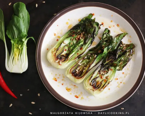 Grillowany pak choi z nasionami słonecznika i papryczką chili na talerzu.