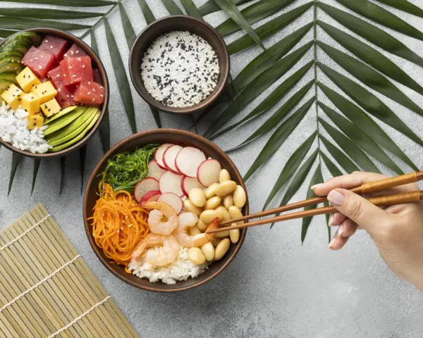 Dwie miski z pysznym sushi: jedna z tuńczykiem, awokado i ogórkiem, druga z krewetkami, fasolką i warzywami.