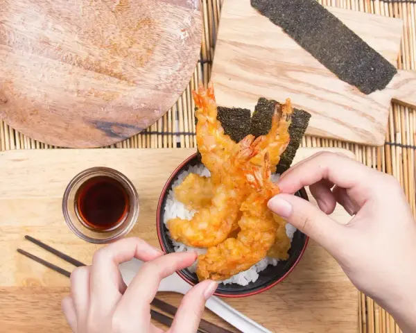 Chrupiące krewetki w cieście tempura na ryżu, gotowe do jedzenia. Idealny przepis na tempurę.